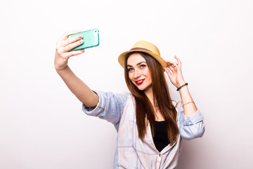 Portrait of a young attractive woman with hat making selfie photo on smartphone isolated on a white background