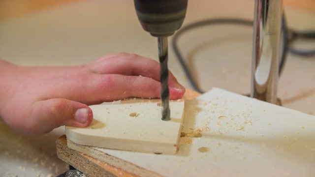 Carefully making a hole in wooden heart close up