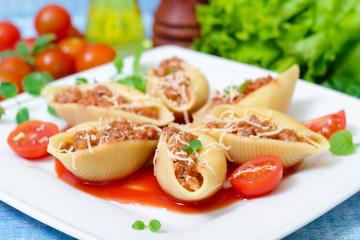 pasta shells stuffed with minced beef meat with herbs and tomato sauce on a plate