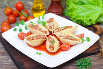 pasta shells stuffed with minced beef meat with herbs and tomato sauce on a plate