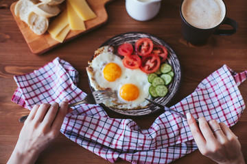 female hands holding devices. Breakfast of scrambled eggs with vegetables , bread and coffee