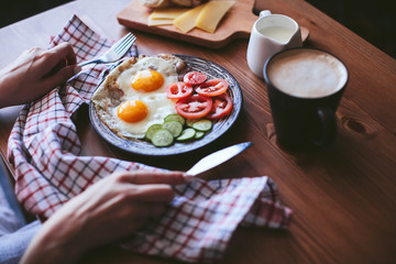female hands holding devices. Breakfast of scrambled eggs with vegetables , bread and coffee