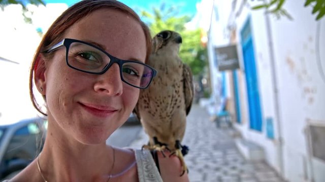 Woman portrait with saker falcon on shoulder