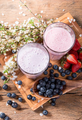 Fresh milk, strawberry, blueberry drinks on wooden table, assorted protein cocktails with fresh fruits.