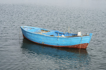 Naklejka na ściany i meble blue coloured wooden boat on sea