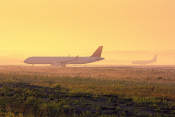 Fototapeta na wymiar Planes on the taxiway in the early foggy morning