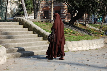 A muslim woman in traditional clothes  jilbab goes on the street