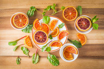 Blood oranges on white plates with salad leaves