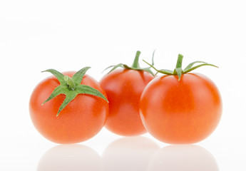 Three cherry tomatoes with reflections, on white background.