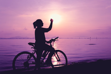 Fototapeta premium Silhouette of happy female celebrating with arm up towards the sun