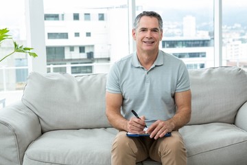 Man sitting on sofa and writing on notepad