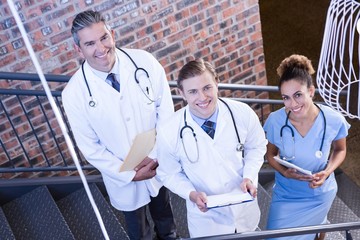 Portrait of doctors standing on staircase with document 