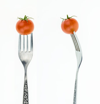 Cherry tomato on fork, front and side view, on white background. © okolaa