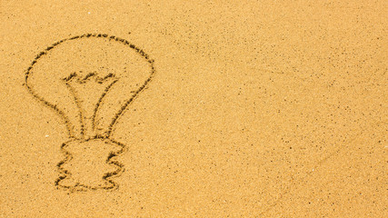 Light bulb drawn by hand on the beach sand.
