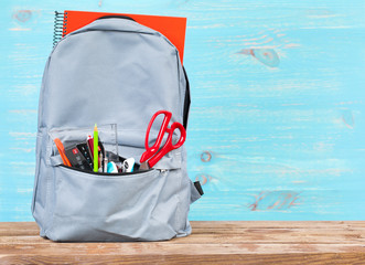Backpack with school tools on turquoise background