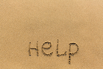 Fototapeta na wymiar Help - word drawn on the sand beach