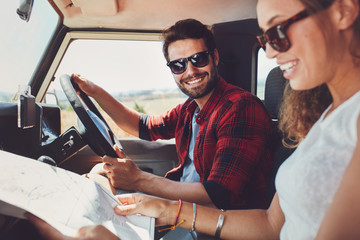 Young couple sitting inside their car with map