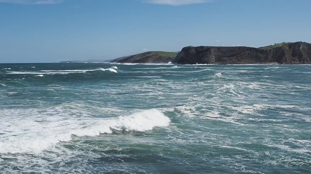 Paisaje mar&iacute;timo visto desde el faro de Comillas en Santander, con olas blancas llegando a la orilla en la primavera de 2016, viajando por Espa&ntilde;a.