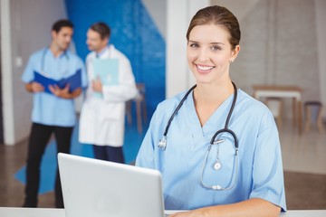 Portrait of happy female doctor with laptop 