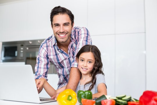 Portrait of smiling father and daughter using laptop 