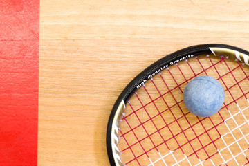 Close up of a squash racket and ball on the wooden background