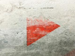 Fading red triangle on a concrete wall
