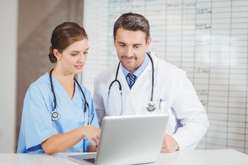 Doctor and colleague working on laptop while discussing