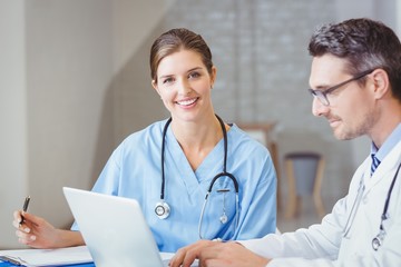 Fototapeta premium Portrait of smiling doctor sitting at desk with colleague 