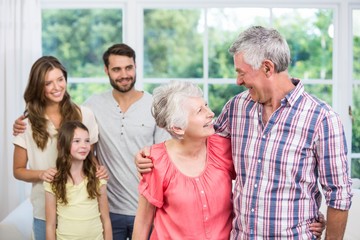 Grandparents embracing while family looking at them
