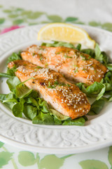 White plate with grilled salmon served with mini spinach and a piece of lemon. Healthy food for family. Home made dinner. Vegetarian lunch for diet.