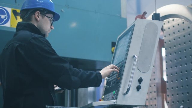 Factory worker is programming a CNC milling machine with a tablet computer. Shot on RED Cinema Camera.