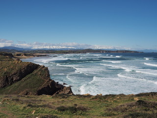 Obraz premium Vistas desde el acantilado verde del paisaje marítimo de Santander con olas blancas llegando a la costa con fuerza en la primavera de 2016, España
