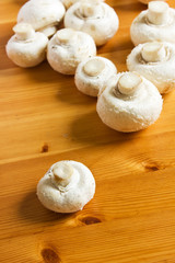 Fototapeta na wymiar White raw champignon closeup lie on a wooden table.