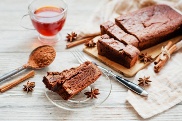 
dessert , chocolate brownie cake with black tea , cinnamon and spices on a wooden background