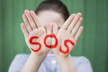The inscription on the hands of SOS, help sign - SOS sign