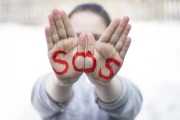 The inscription on the hands of SOS, help sign - SOS sign
