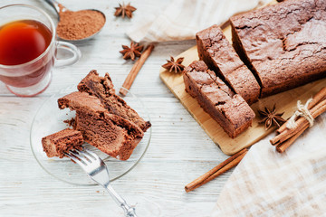 
dessert , chocolate brownie cake with black tea , cinnamon and spices on a wooden background