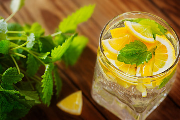 Lemonade with fresh lemon and mint on wooden background