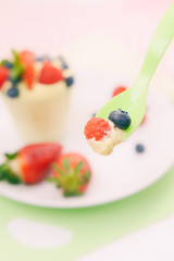 Babylöffel mit Joghurt und Obst gefüllt. Auf den Betrachter zukommend.