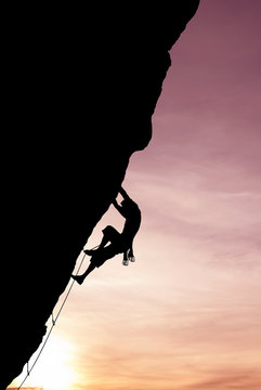Silhouette of climber on rock face vertical image