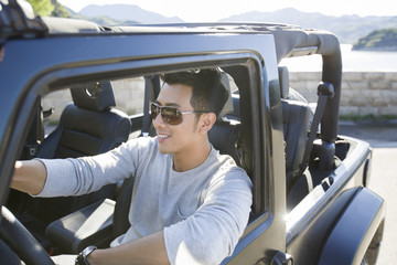 Happy young man driving a jeep