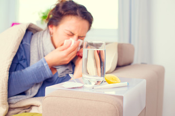 Fototapeta na wymiar Sick woman sneezing into tissue. Flu. Woman caught cold