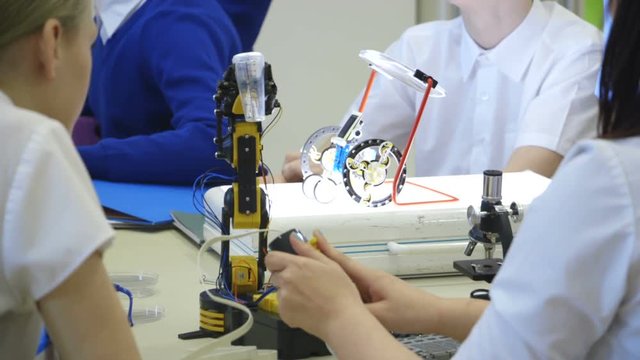 Students using robotic arms in a technology lesson.