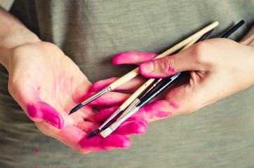 Female artist hands covered with pink paint