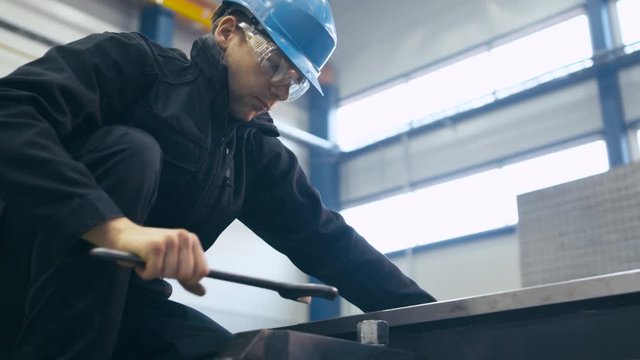 Industrial worker is tightening screws with a wrench at a factory.  Shot on RED Cinema Camera.