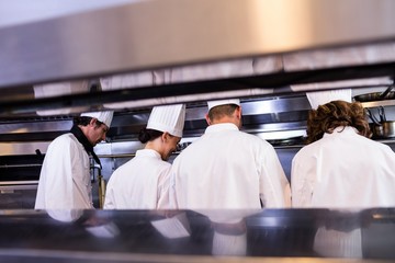 Group of chefs in white uniform busy to preparing food