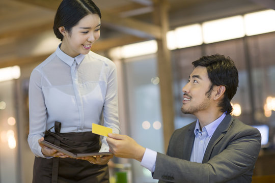 Businessman paying bill by credit card in restaurant