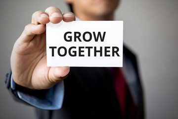 Businessman presenting 'Grow Together' word on white card