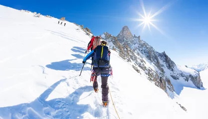  Bergbeklimmers beklimmen een besneeuwde top. Op de achtergrond de beroemde piek Dent du Geant in het Mont Blanc-massief, de hoogste Europese berg. De Alpen, Chamonix, Frankrijk, Europa. © rcaucino