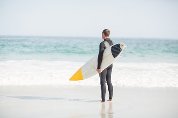 Surfer standing on the beach with a surfboard